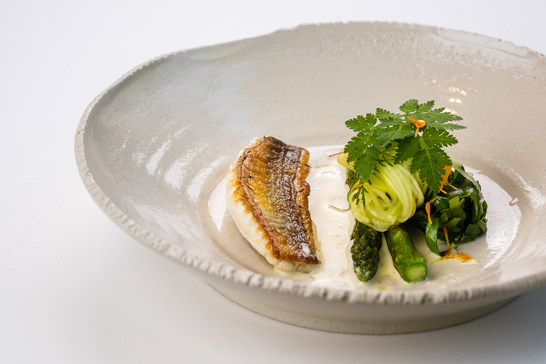 https://hungryformore.be/app/uploads/2024/12/de-jonkman-bruges-fish-with-green-vegetables-in-a-white-bowl.jpg