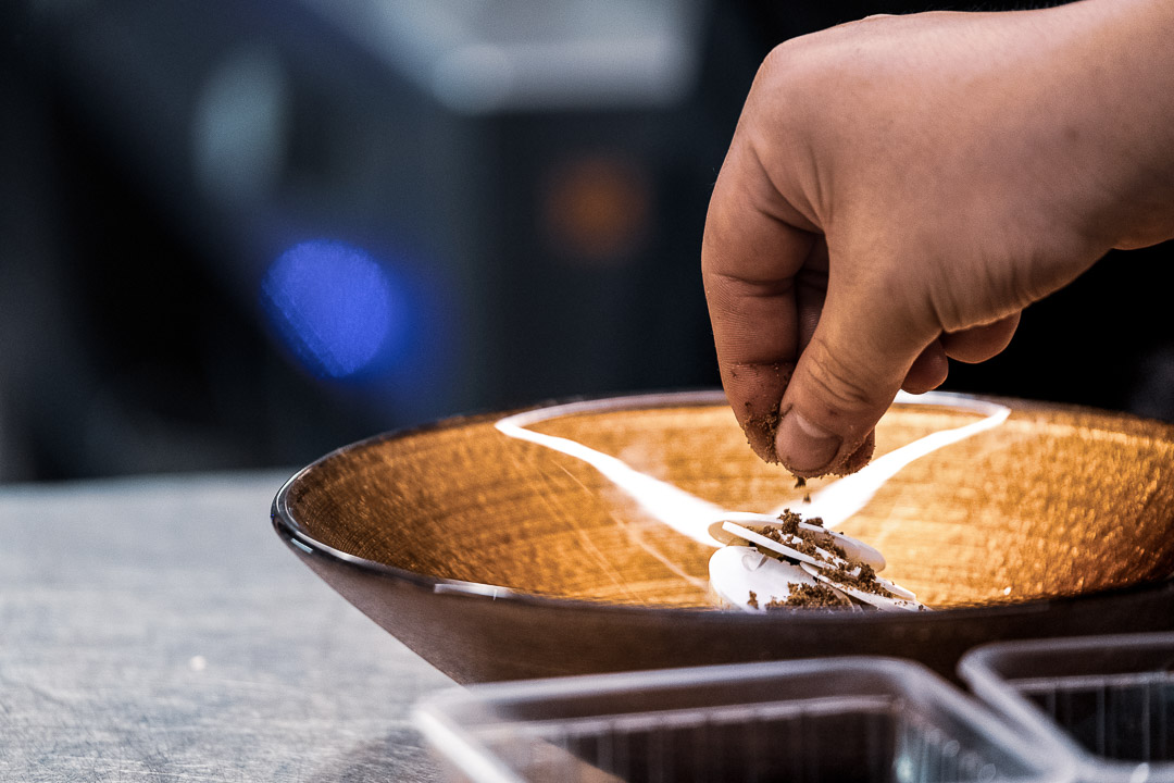 https://hungryformore.be/app/uploads/2024/12/de-jonkman-bruges-hand-finishing-a-dish-in-a-bowl.jpg