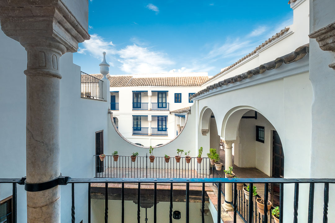 https://hungryformore.be/app/uploads/2024/12/las-casas-de-la-juderia-cordoba-building-with-arches-seen-from-the-balcony.jpg
