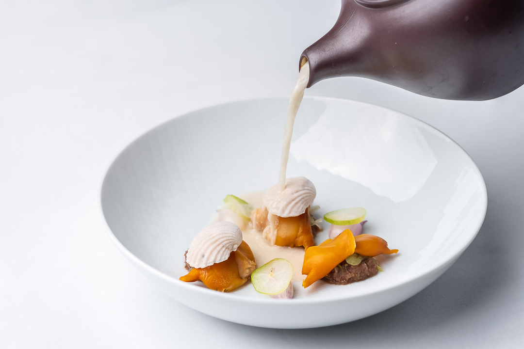 https://hungryformore.be/app/uploads/2024/12/sukhothai-bangkok-coconut-soup-being-poured.jpg