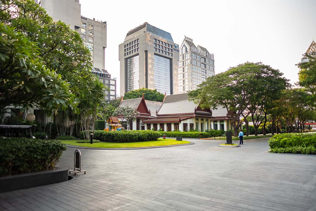 https://hungryformore.be/app/uploads/2024/12/sukhothai-bangkok-hotel-driveway-and-garden.jpg